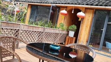 A dining area with a round table, wicker chairs, and a view of a traditional building with a tiled roof.