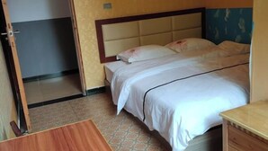 Une chambre d’hôtel avec un lit, une table de chevet en bois et une porte donnant sur une autre pièce.