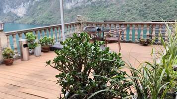 A wooden deck with potted plants, outdoor furniture, and a view of a mountainous landscape.