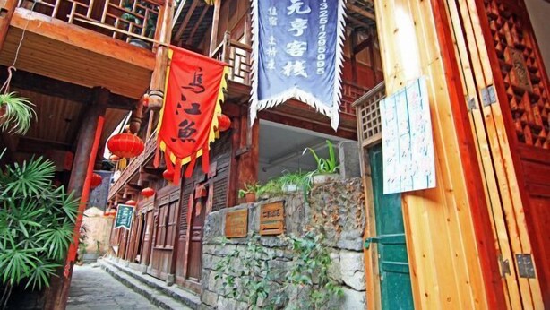 Un bâtiment traditionnel en bois, doté d’un balcon, de lanternes rouges et d’une enseigne.