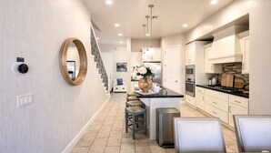 A modern kitchen with a central island, stainless steel appliances, and a staircase leading to an upper level. - Get together at Zion`s Gate l & ll! (Washington)