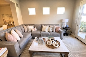 A living room with a grey sectional sofa, a marble coffee table, and three wall-mounted lights.