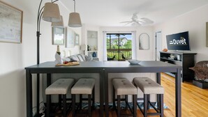 A modern kitchen with a central island, bar stools, pendant lighting, and a view to the outdoors. - Seabrook Marsh Views | Amenity Card! | Pool Access (Seabrook Island)
