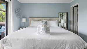 A neatly made bed with a towel stack, a bedside lamp, and a decorative wall piece. - Seabrook Marsh Views | Amenity Card! | Pool Access (Seabrook Island)
