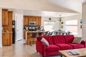 A modern kitchen with wooden cabinets, a microwave, and a dining area with a red sofa and a coffee table. - Pet friendly, Zion, Private Hot Tub (La Verkin)