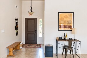 A hallway with a wooden bench, a dark door, a small table with a lamp, and a framed artwork on the wall. - Pet friendly, Zion, Private Hot Tub (La Verkin)
