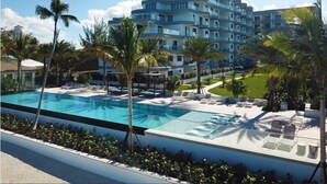 A modern hotel with a large swimming pool, multiple balconies, and lush greenery. - One Cable Beach (Nassau)
