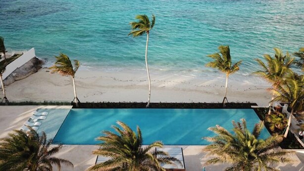 A pool with a view of the ocean and palm trees. - One Cable Beach (Nassau)