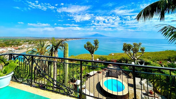 A pool area with a view of the sea and a distant mountain.