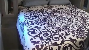 Un lit avec une couvre-lit à motifs, une tête de lit et une petite étagère au-dessus du lit.