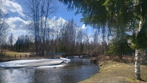 Un río con parches de hielo, rodeado de árboles y un cielo despejado.