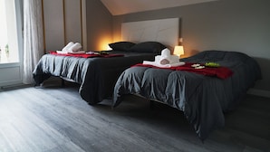 Une chambre d’hôtel avec deux lits, une grande fenêtre avec des rideaux et une table de chevet avec une lampe.