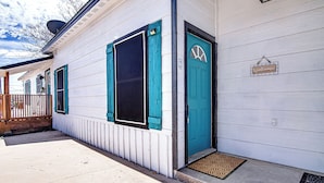 A white building with teal shutters and a blue door, featuring a welcome sign and a number '2' sign. - Old Town Rodeo Studio. Free parking. Walk to entertainment and restaurants. (Burleson)