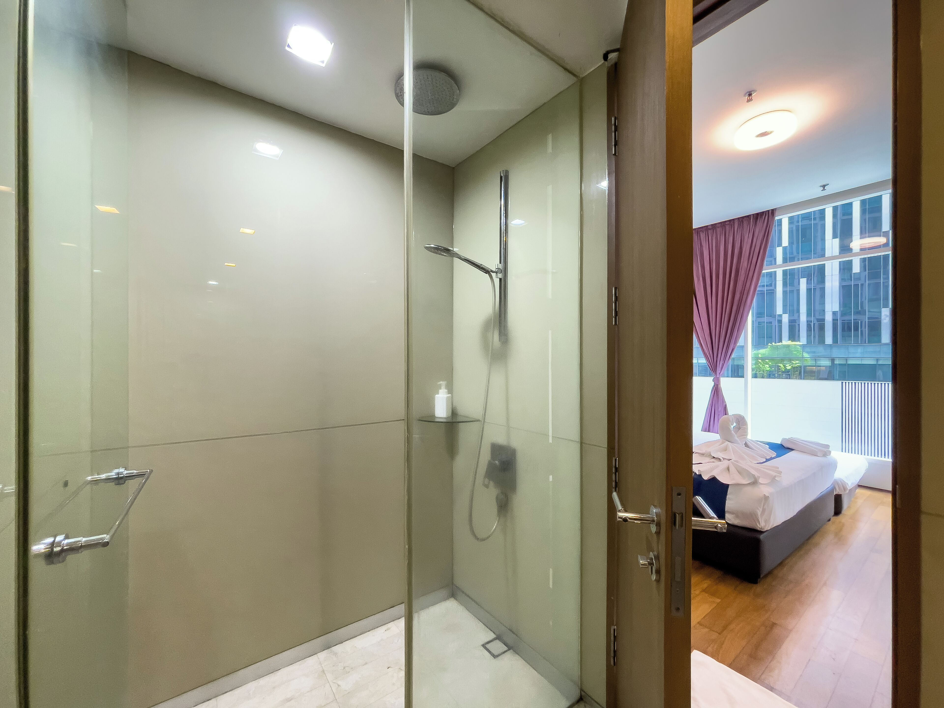 A modern bathroom with a glass-enclosed shower, a glass door, and a visible towel rack.
