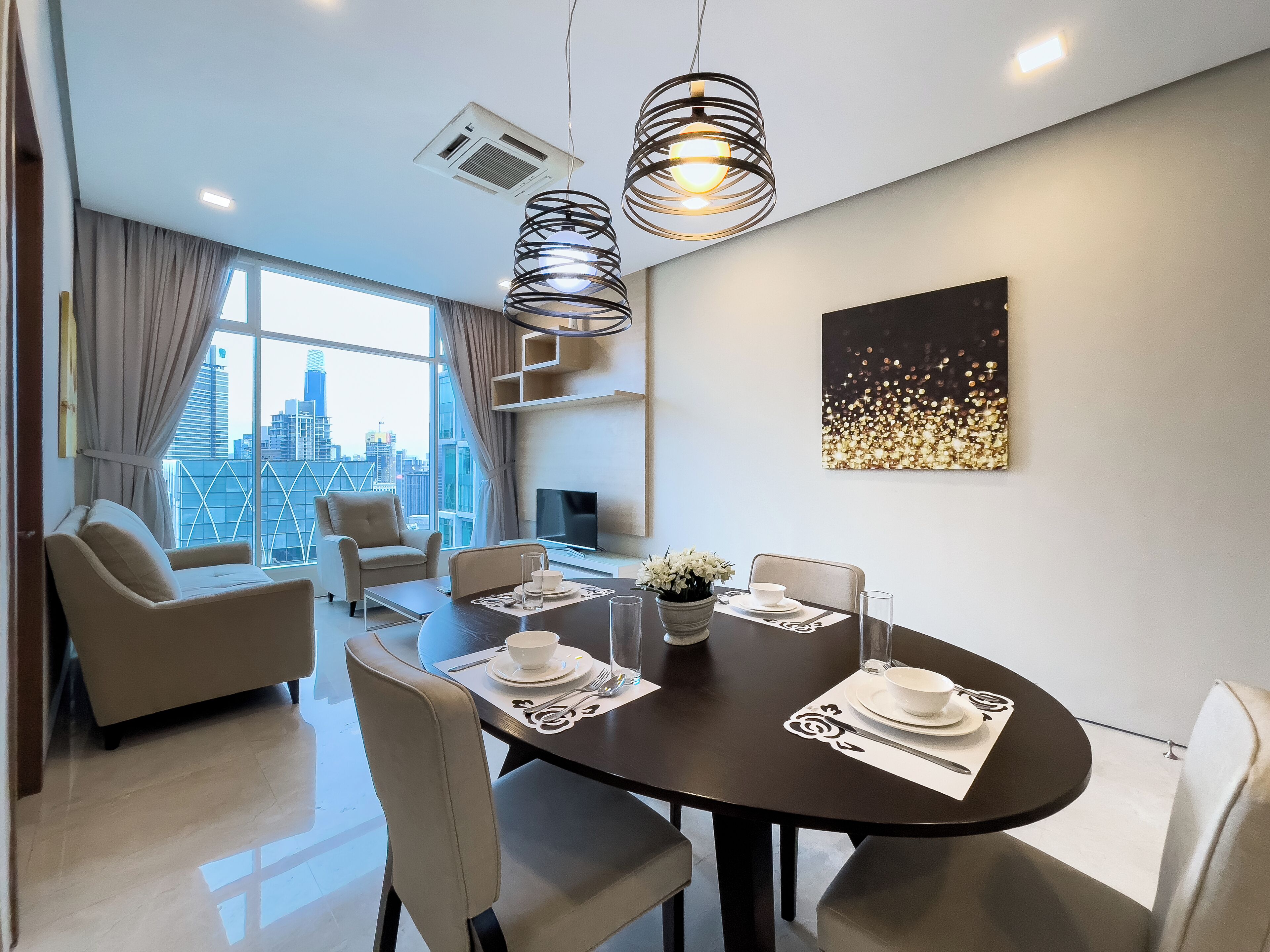 A modern dining area with a round table, chairs, and a city view.