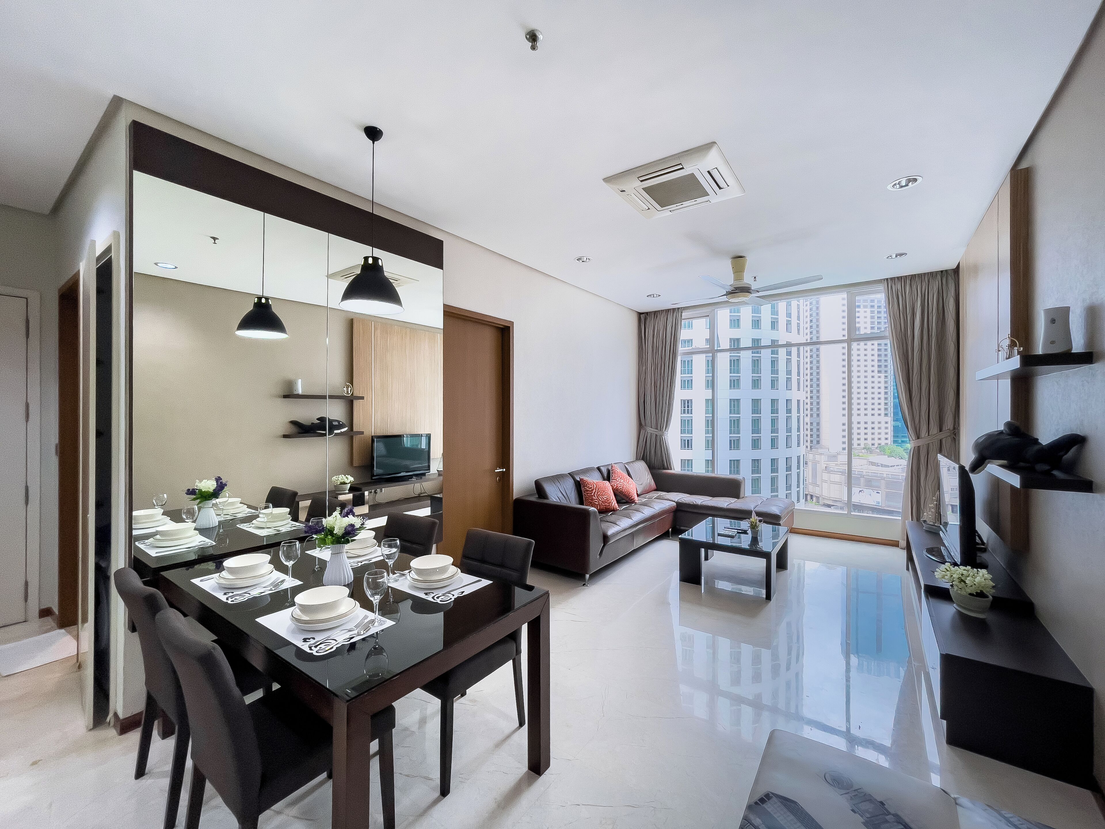 A modern living room with a dining area, large windows, and a city view.
