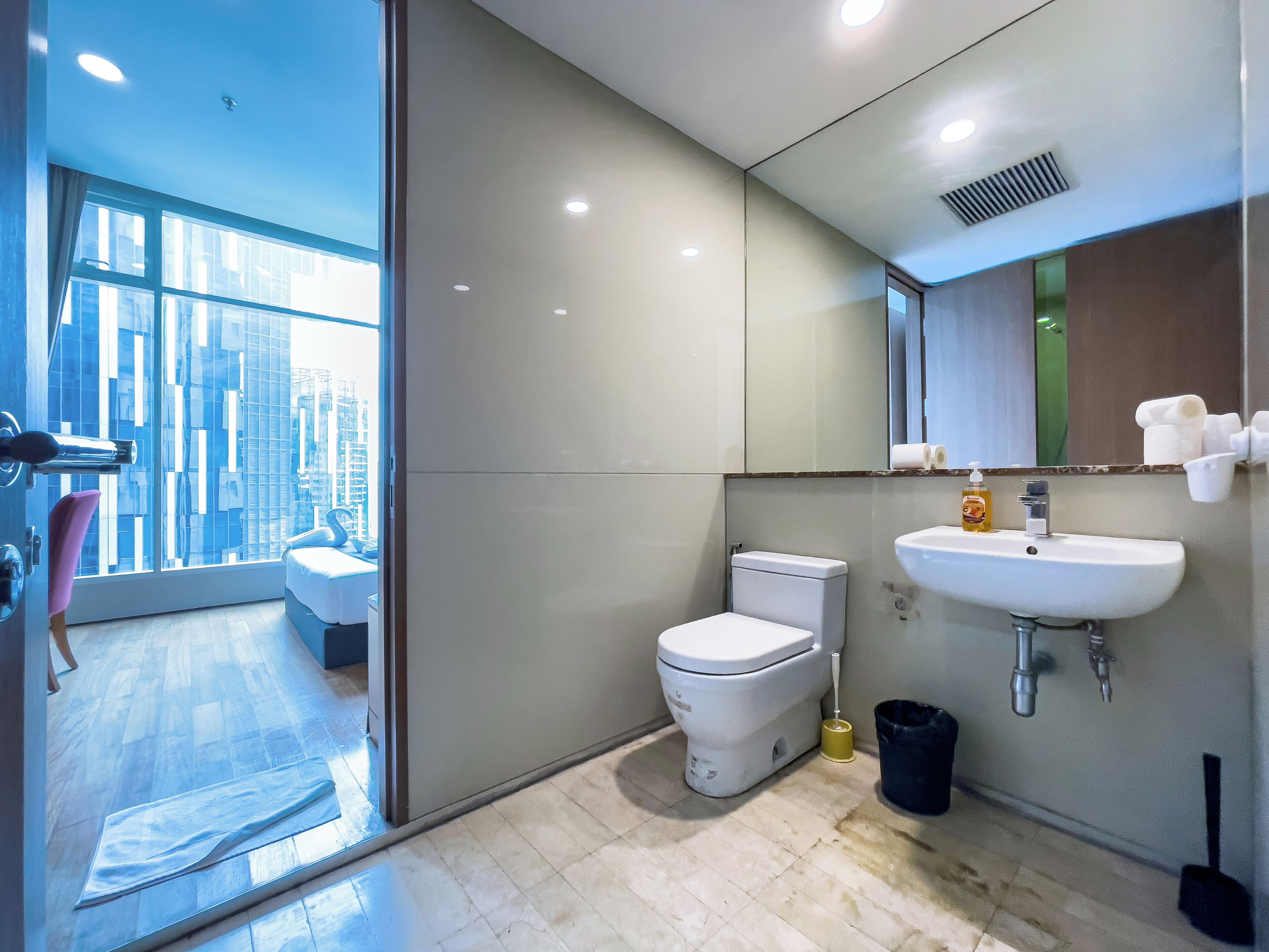 A modern bathroom with a toilet, sink, and large mirror.