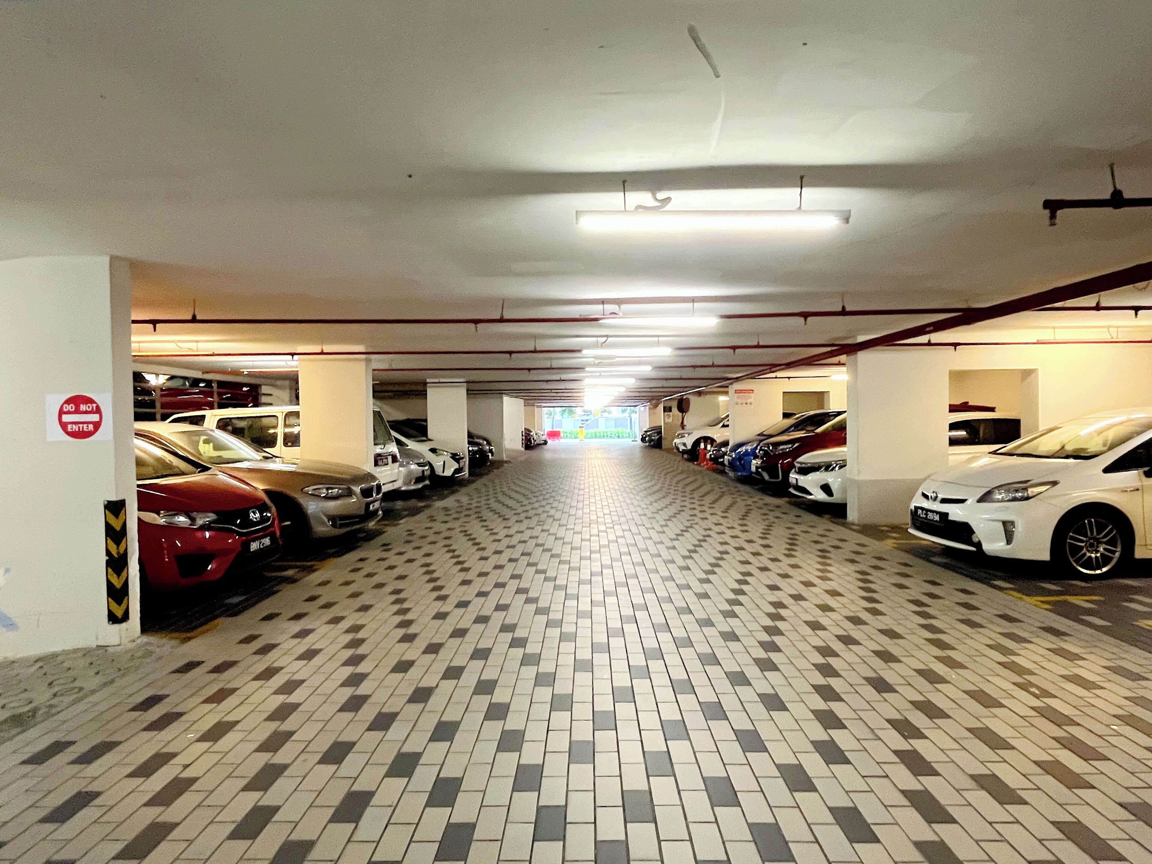 Un estacionamiento de varios niveles con automóviles aparcados a ambos lados de un pasillo central.