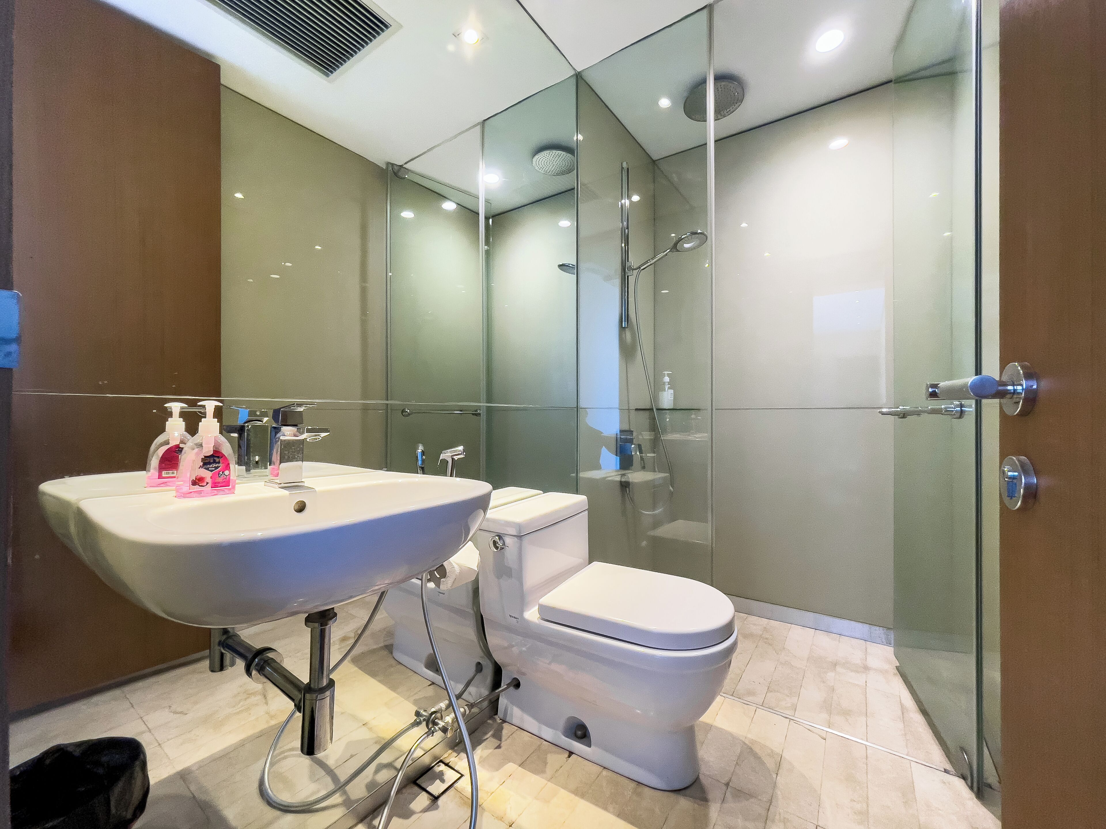 A modern bathroom with a glass-enclosed shower, a white sink, and a toilet.