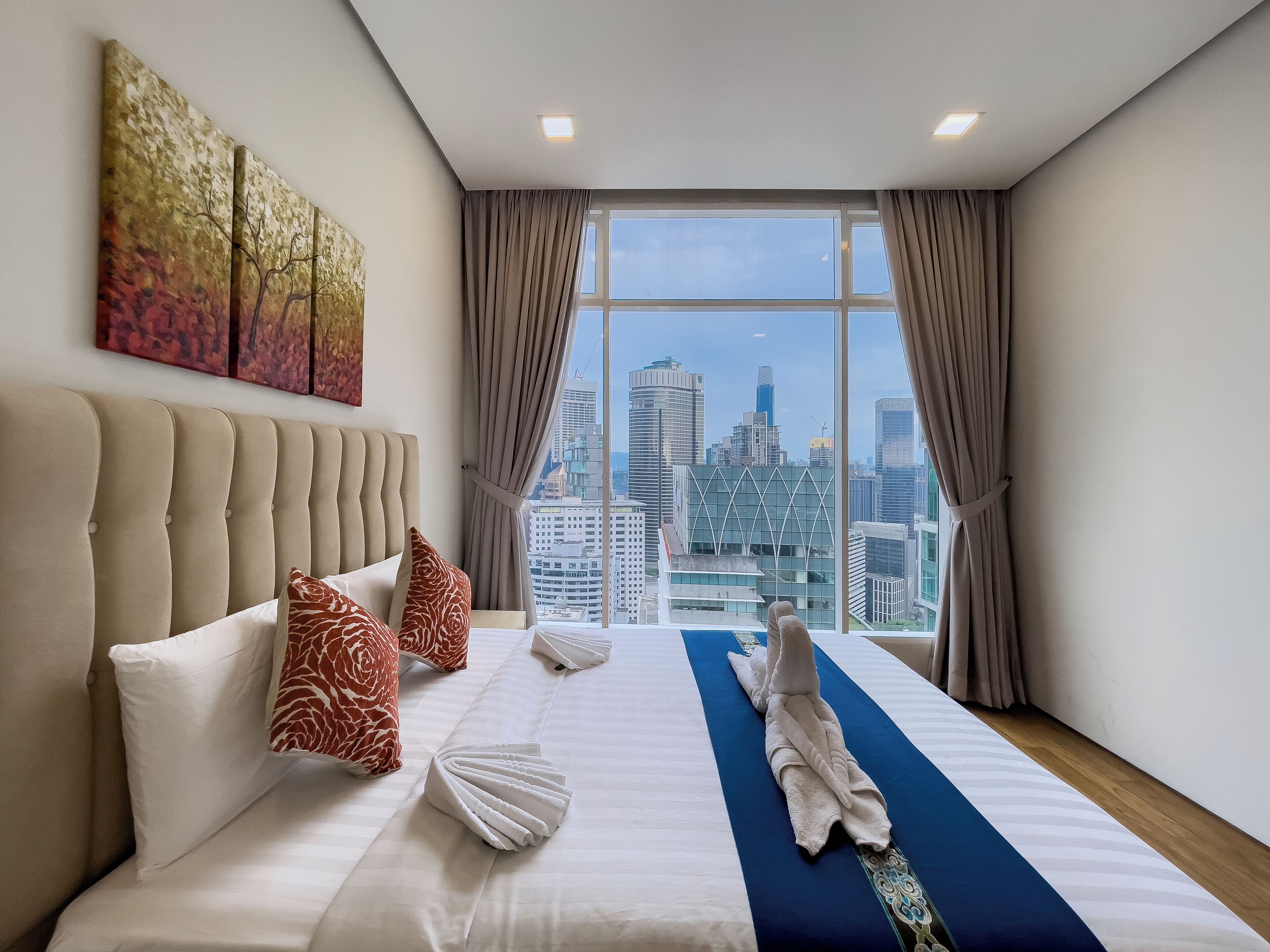 A hotel room with a large bed, a view of the cityscape, and a modern design.