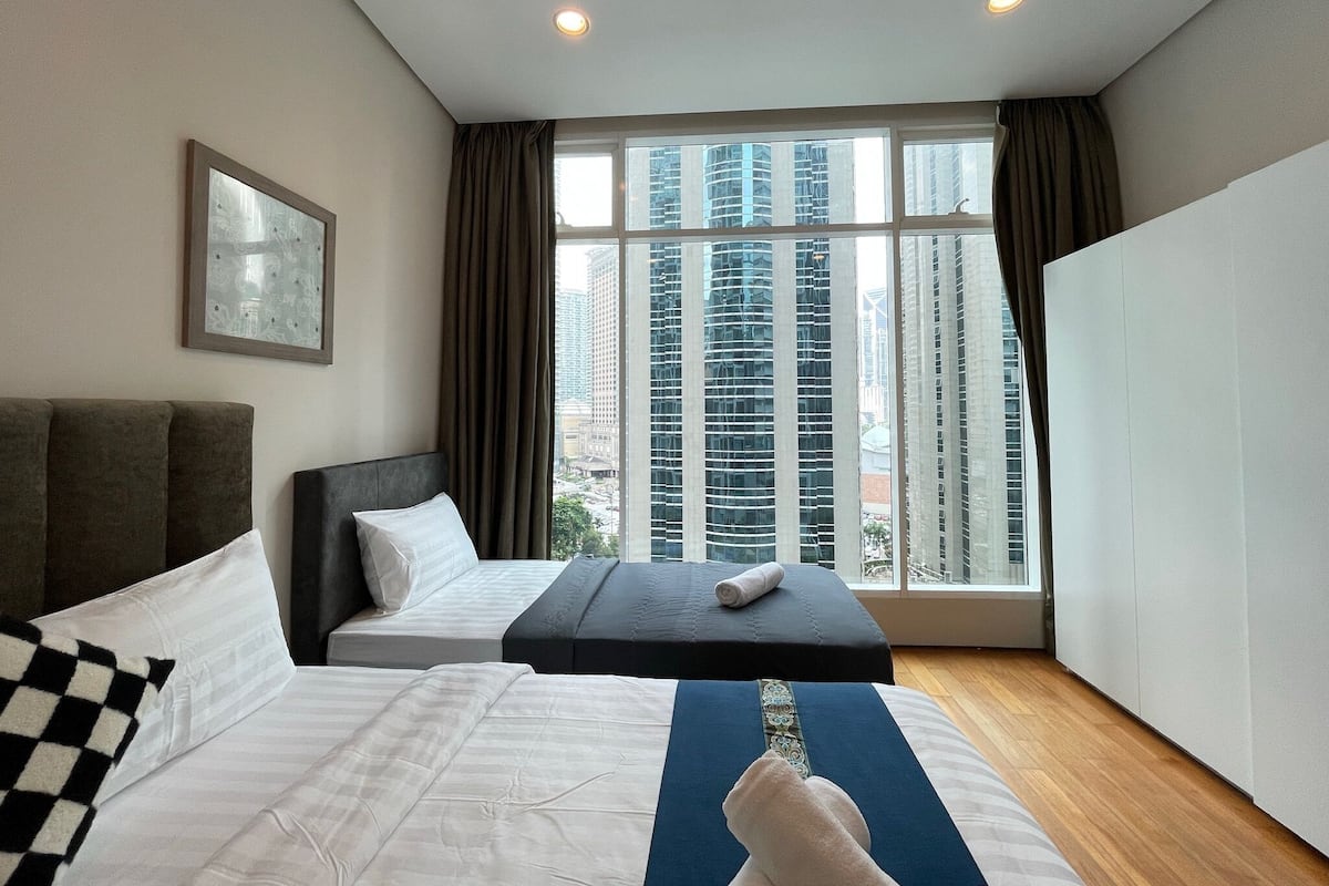 Une chambre d’hôtel avec une grande fenêtre, un lit, un canapé et une table de massage.