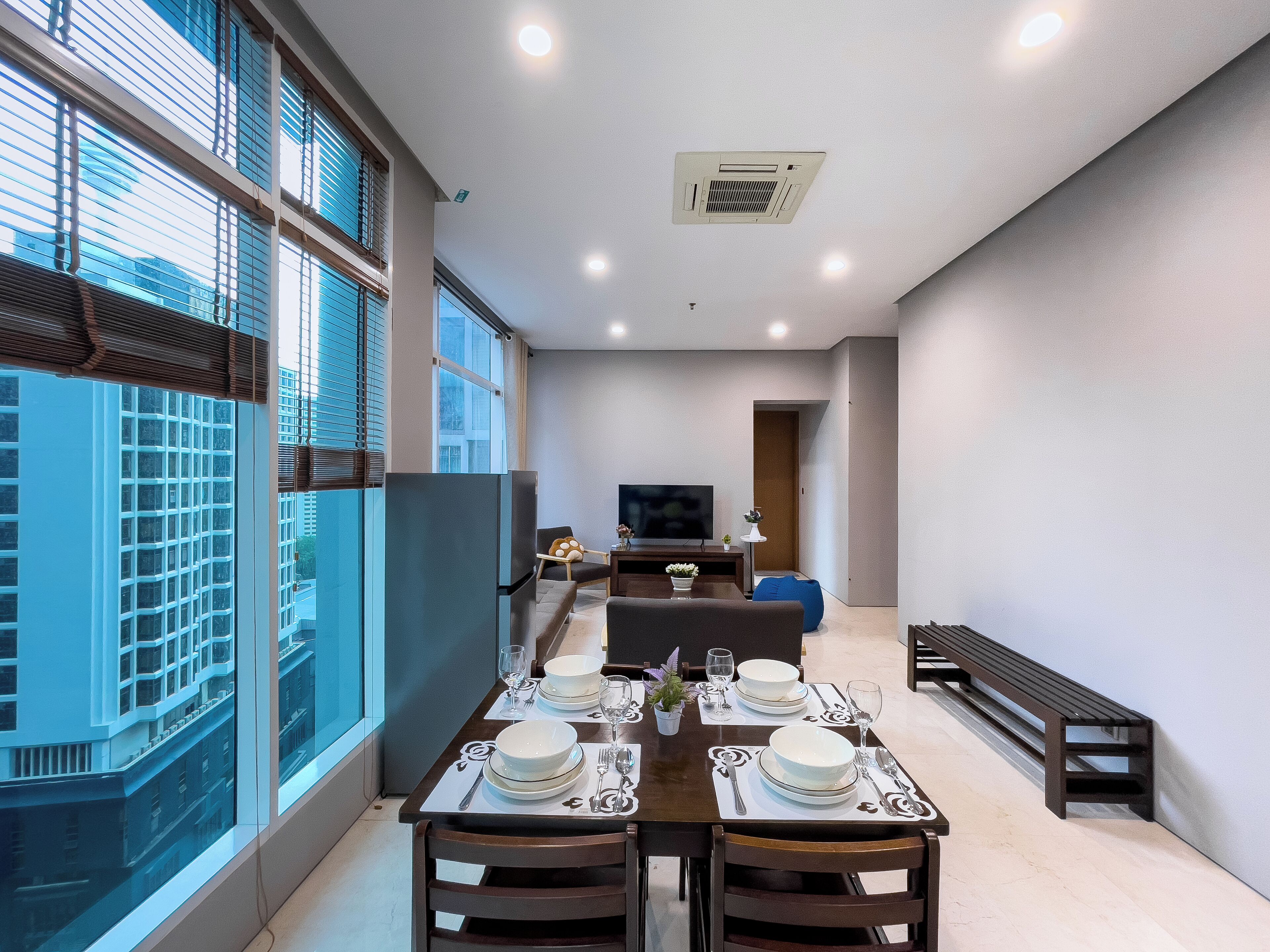 A modern dining area with a table set for four, a sofa, and a TV in the background.