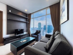 A modern living room with a city view, a flat-screen TV, a glass coffee table, and a sofa. - Soho Suites KLCC By Rest Kuala Lumpur (Kuala Lumpur)