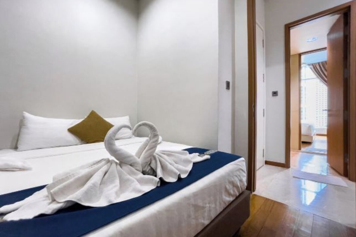Une chambre d’hôtel avec un lit bien fait, une couvre-lit bleue et un oreiller doré.
