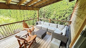 A wooden deck with wicker furniture, including a sofa and chairs. - Reenie’s Rustic Retreat - Walking distance to beach, Pet friendly!  (Swansea Point)