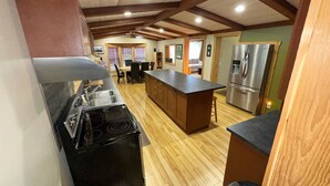 A kitchen with wooden floors, a central island, a stove, and a refrigerator. - Reenie’s Rustic Retreat - Walking distance to beach, Pet friendly!  (Swansea Point)
