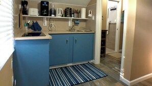 Une cuisine de taille réduite avec des meubles bleus, une machine à café et une bouilloire posées sur le plan de travail.