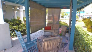 Un patio couvert aménagé avec un canapé, des fauteuils et une chaise berçante.