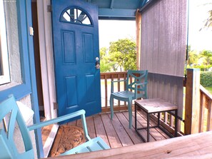 A wooden deck with a blue door, a chair, and a table. - Kestrel - Best location in Nassau, Kestrel Bahamas Vacation Rental (Nassau)