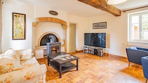 A living room with a fireplace, TV, sofa, and coffee table. - Le Petit Chambi - CHAMBILLY (CHAMBILLY)