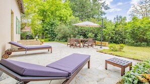 A patio with two sun loungers, a table with chairs, and an umbrella. - Le Petit Chambi - CHAMBILLY (CHAMBILLY)