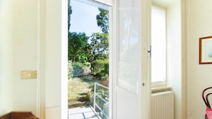 A room with a view of a garden, a radiator, a chair, and a door. - Imperatrice apartment by Wonderful Italy (Sanremo)