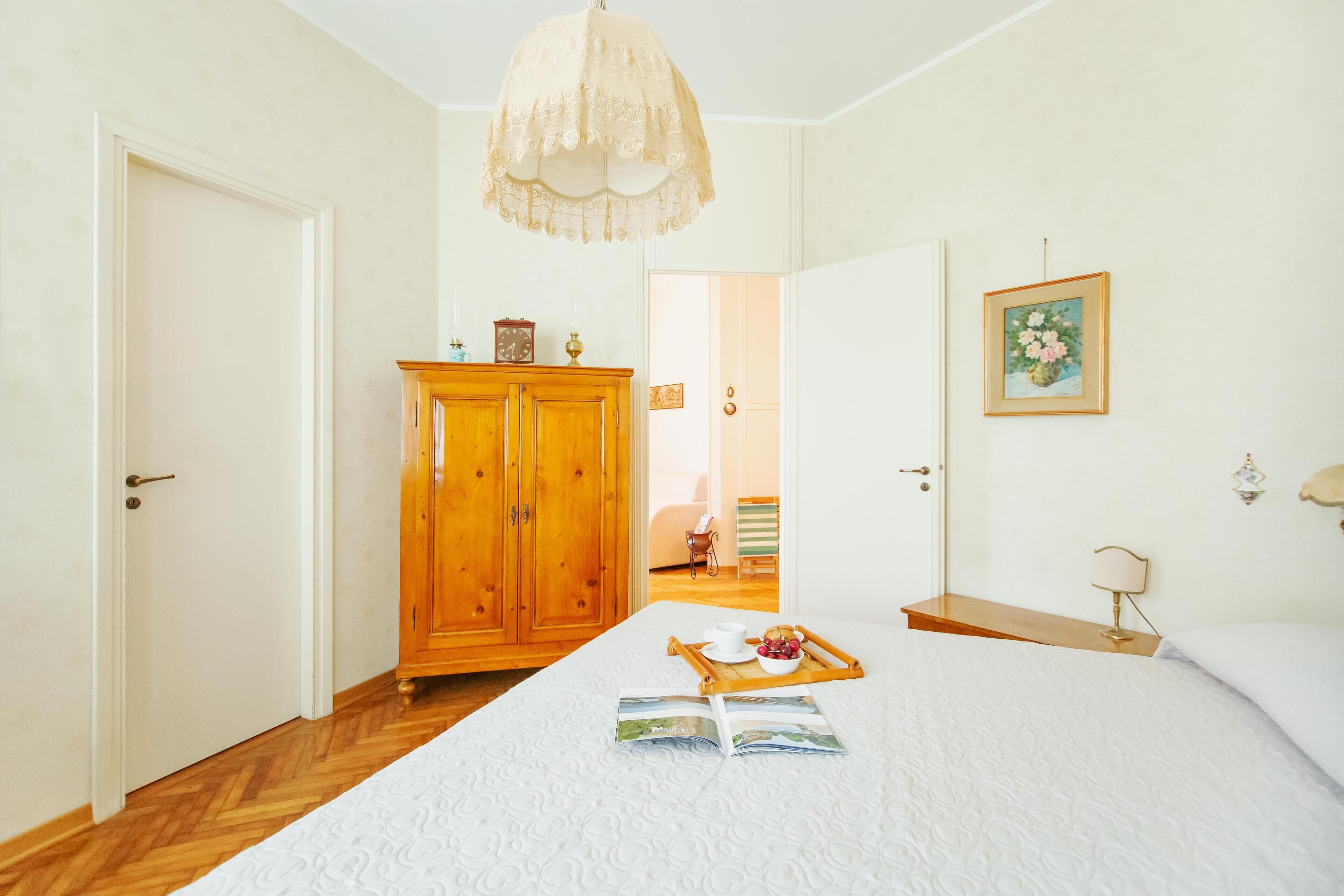 A bedroom with a large bed, wooden wardrobe, and a bedside table with a lamp.