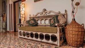 Un sofá antiguo con cojines estampados, un florero texturizado y un suelo con diseño.