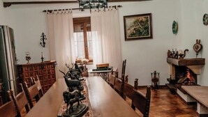 Un comedor con una larga mesa de madera, sillas, una chimenea y una ventana con cortinas.