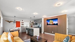 A modern living room with a sofa, a coffee table, and a TV mounted on a wooden wall.