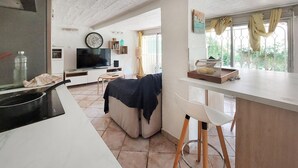Una cocina moderna con televisor, un comedor con barra y vistas a zonas verdes.