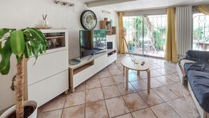 Una sala de estar con televisor, mesa de centro, sofá y planta en maceta.