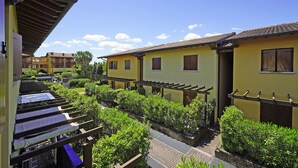 A courtyard with a pergola, a yellow building, and a brick pathway.