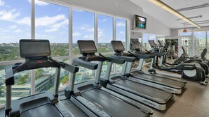 Une salle de sport équipée de tapis de course, de vélos d’exercice et de poids.
