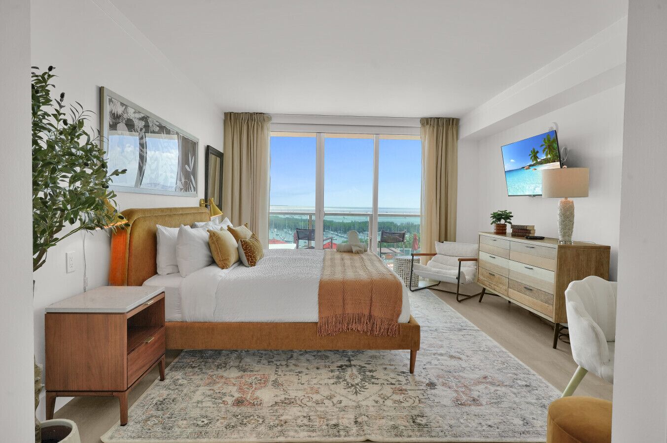 Ein modernes Hotelzimmer mit einem großen Bett, einem Schreibtisch, einem Sessel und Blick auf die Stadt.