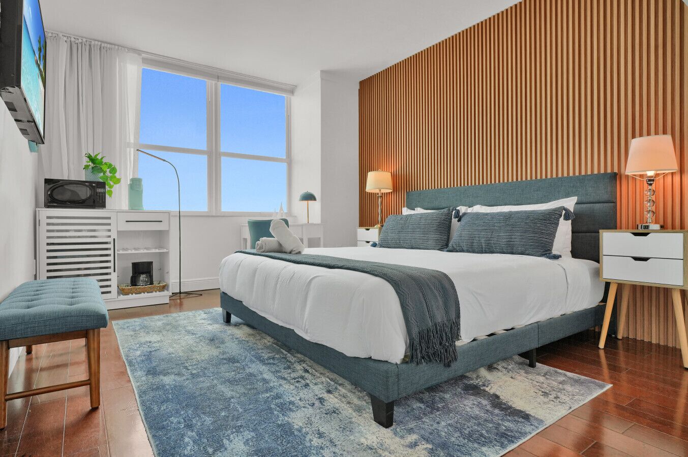 A modern bedroom with a large bed, bedside tables, a desk, and a TV.