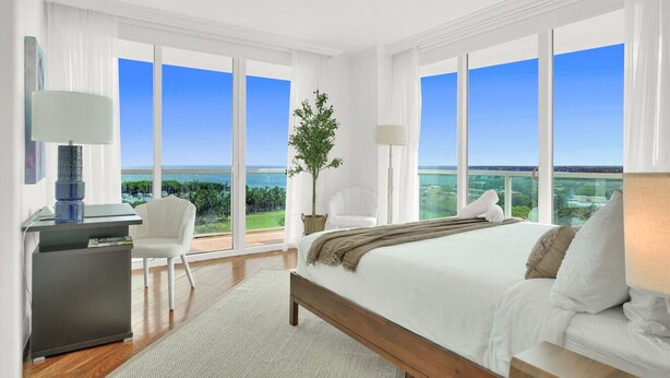 Une chambre spacieuse dotée d’un grand lit, d’un bureau et d’une chaise, et offrant un balcon avec une vue dégagée sur l’océan.