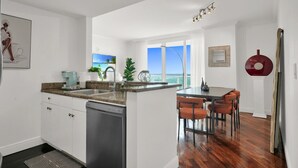 Une cuisine moderne dotée de plans de travail en granit, d’un lave-vaisselle et d’un coin repas avec des chaises orange.