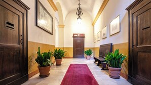 A hallway with a red carpet, wooden doors, and potted plants. - Studio nel Cuore della Citta' by Wonderful Italy (Bologna)