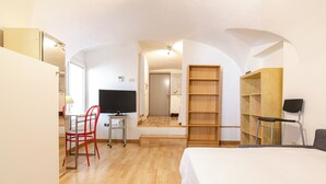 A modern hotel room with a bed, a desk with a chair, a TV, and built-in shelving. - Studio nel Cuore della Citta' by Wonderful Italy (Bologna)
